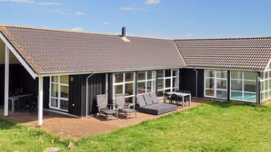 A house with a covered patio, outdoor seating, and a swimming pool. - 12 Person Holiday Home in Pandrup (Pandrup)