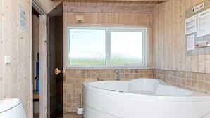 A bathroom with a large bathtub, a toilet, and a window providing a view of the outdoors. - 12 Person Holiday Home in Pandrup (Pandrup)