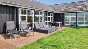 Ett modernt hus med en stor terrass, utomhusmöbler och en swimmingpool.