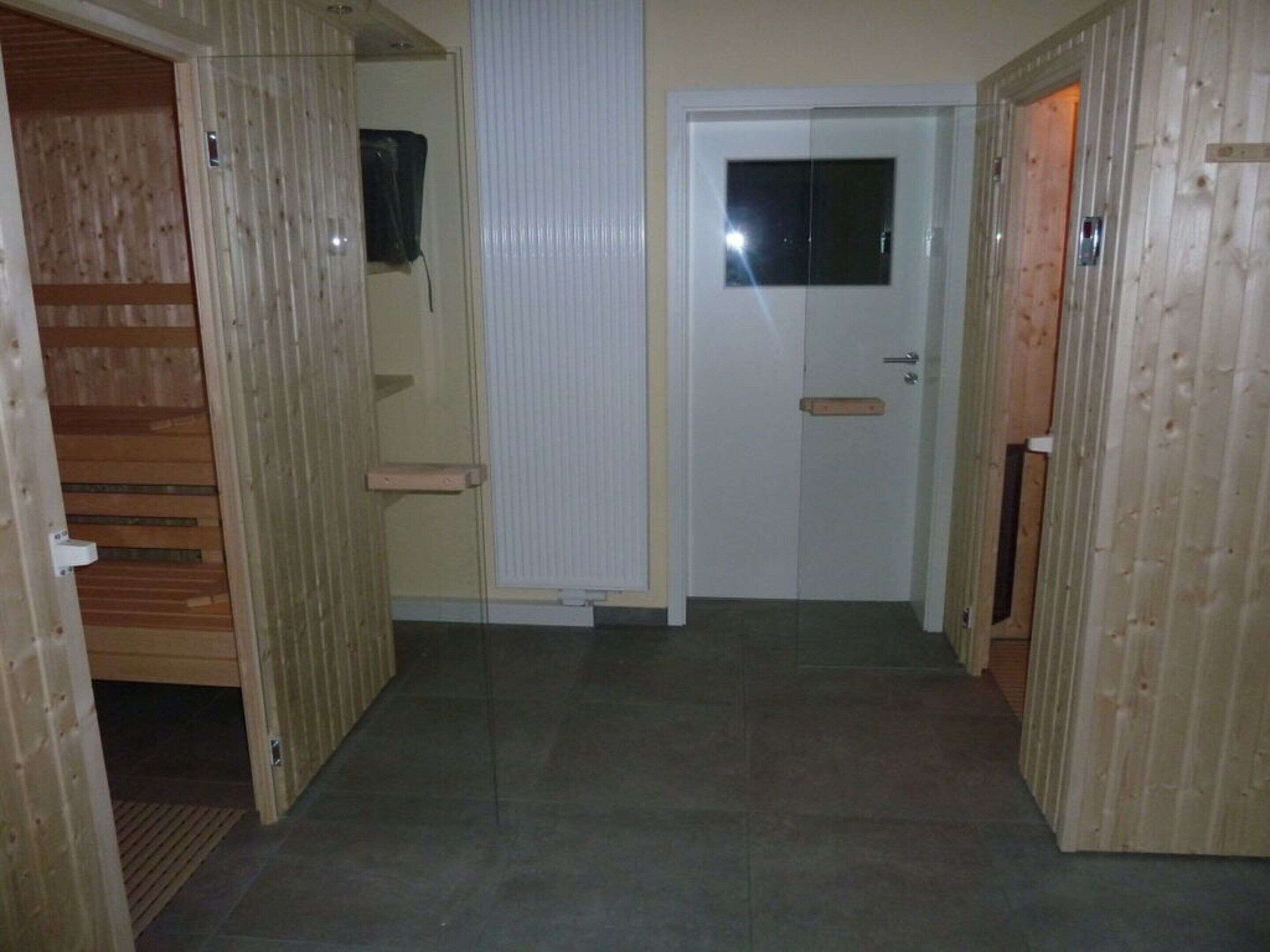 A hallway with wooden paneling on the walls, a white door with a window, and a small shelf.