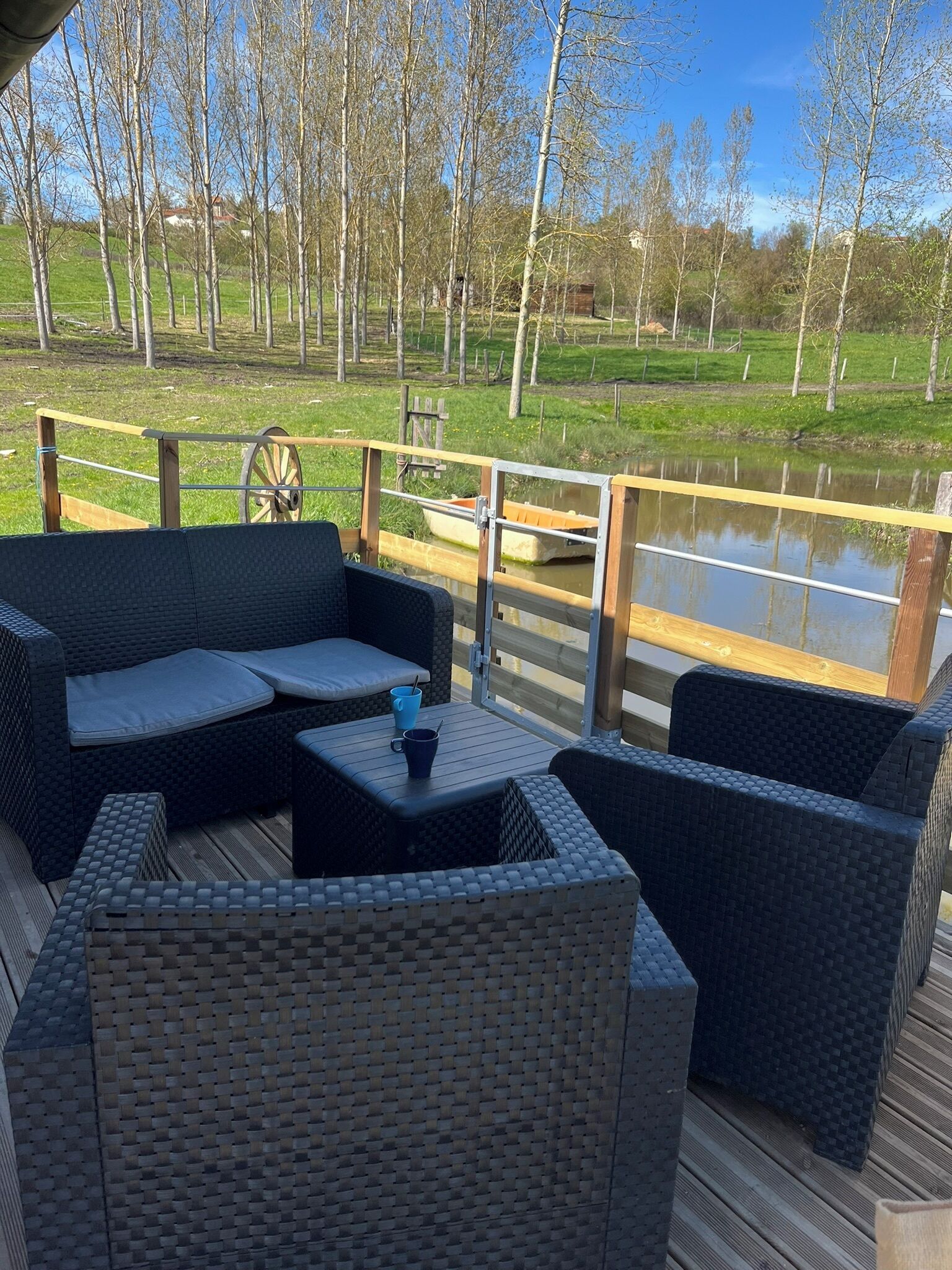 An outdoor deck with wicker furniture and a view of a lake.