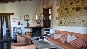 Ein gemütliches Wohnzimmer mit Kamin, einer Couch, einem Couchtisch und einem Bücherregal.