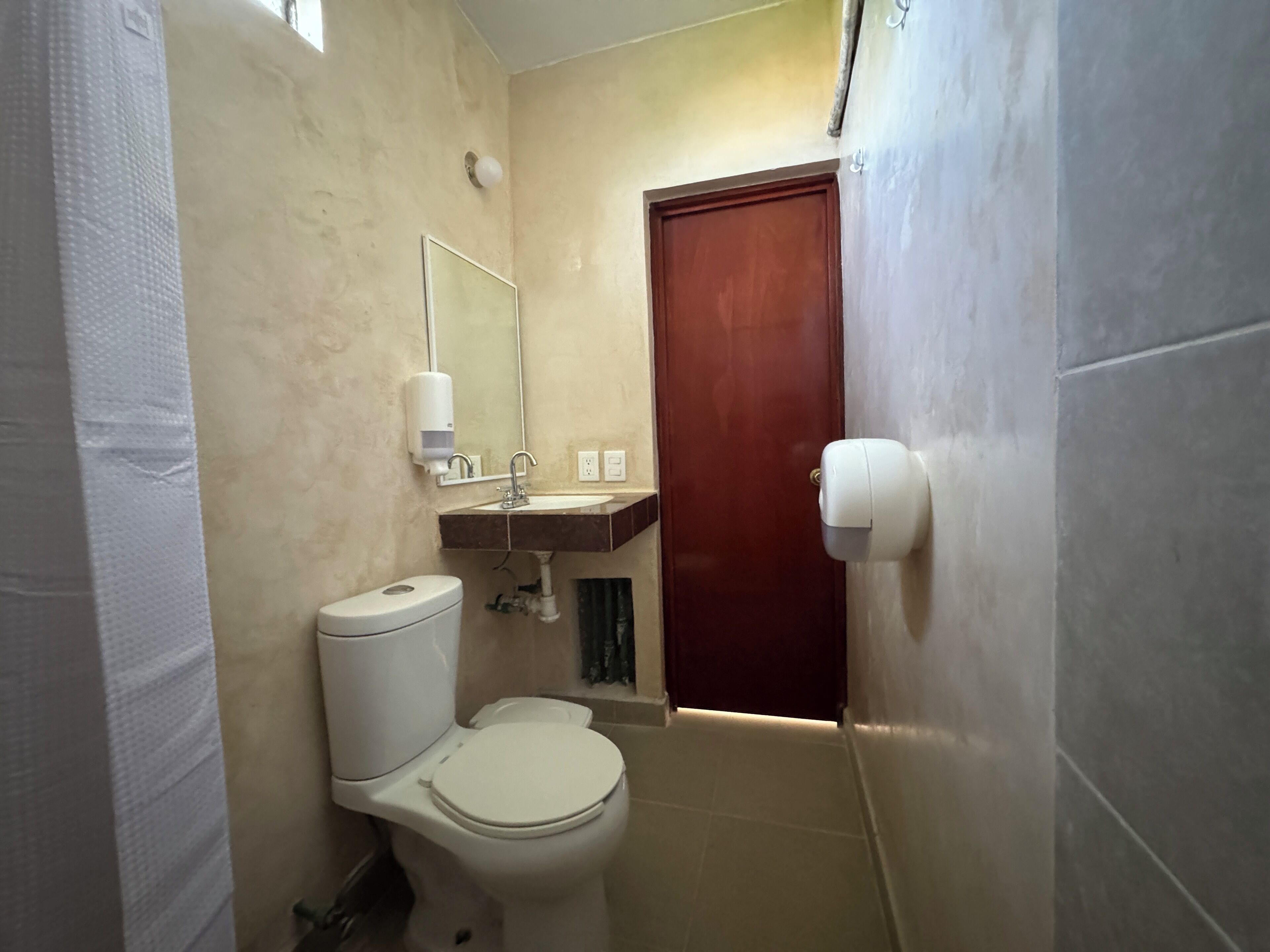 Une petite salle de bain avec des toilettes, un lavabo et un miroir.