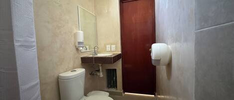 A small bathroom with a toilet, sink, and mirror.
