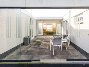 A modern interior with a glass partition, a seating area with chairs, and a view of the outside.