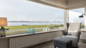 A room with a view of a lake, a radiator, a lamp, and a chair with a cushion. - Holiday Home by Lake Veerse Meer (Kamperland)