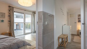 A modern bedroom with a bed, a small wooden stool, and a view of the outside through a sliding glass door. - Holiday Home by Lake Veerse Meer (Kamperland)