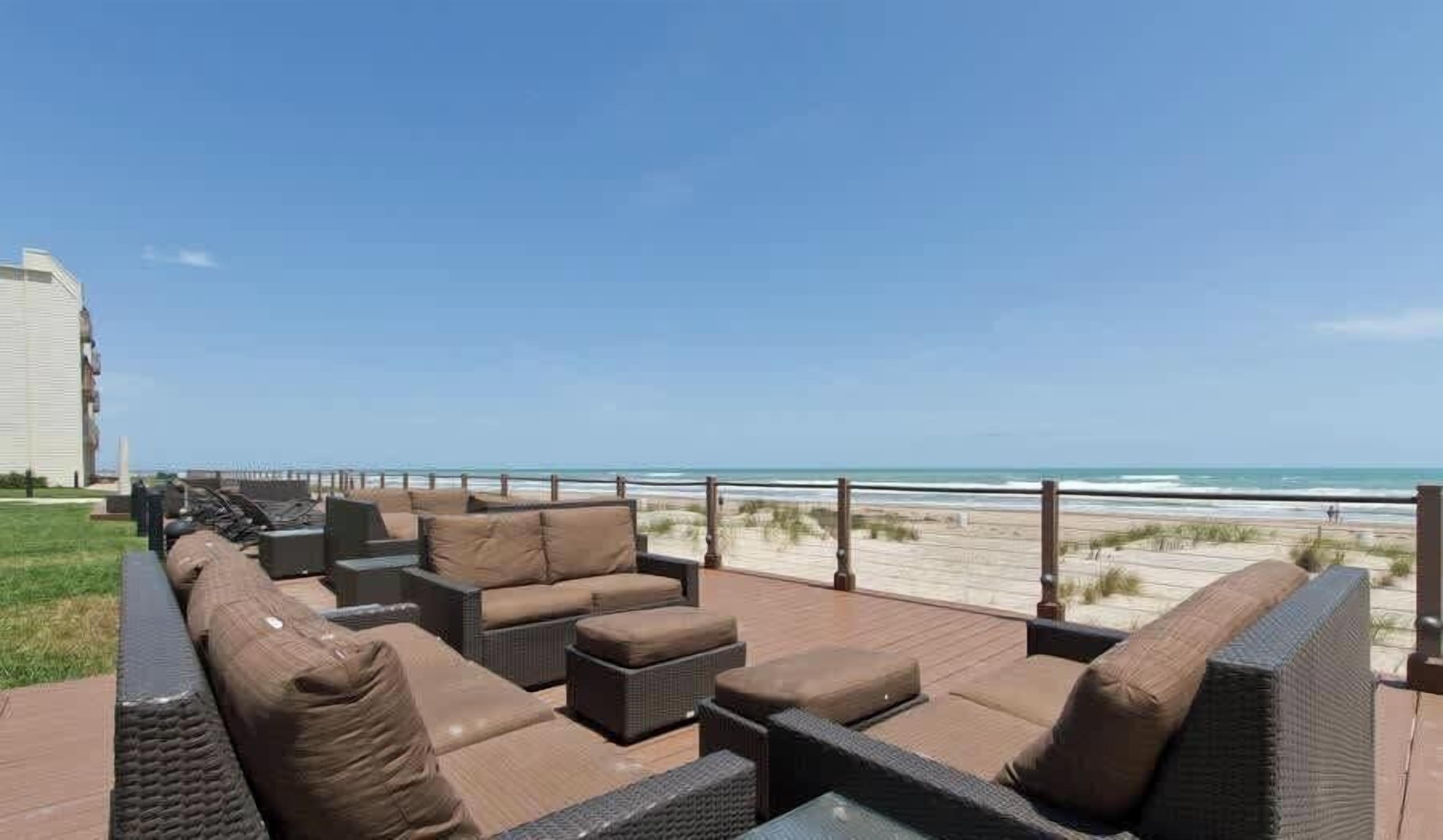 A deck with outdoor seating overlooking a beach.