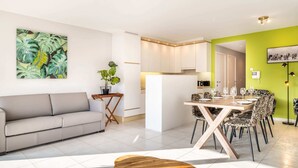 Un salon moderne avec un canapé, une table basse en bois et un coin repas comprenant une table et des chaises.