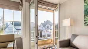 Un salon moderne doté d’une porte-fenêtre coulissante donnant sur un balcon, d’un canapé beige et d’un tapis coloré placé devant la porte.
