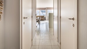 Un couloir avec deux portes donnant sur un coin repas équipé d’une table et de chaises.