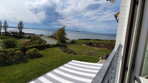 A balcony with a view of a landscaped garden, a curved road, and a body of water in the distance. - Nice Apartment Near Seabeach (Stein)