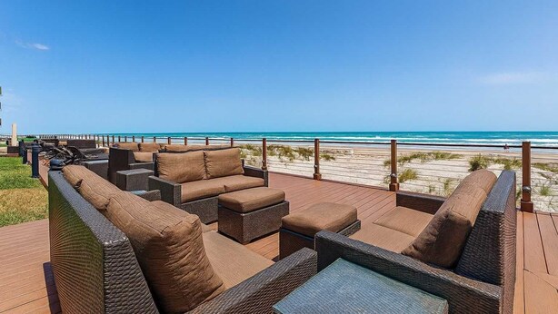 Een terras met rieten meubilair met uitzicht op een strand.