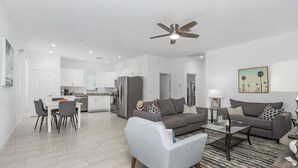 A modern apartment with a dining area, two sofas, a coffee table, and a ceiling fan. - Seas the Day Beach Wine Dine Relax (Naples)