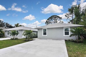 A two-story residential house with a grey exterior, white trim, and a concrete driveway.