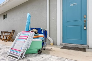 A blue door with the number 852A, a green and white cooler, a striped beach chair, and a blue and white beach chair.