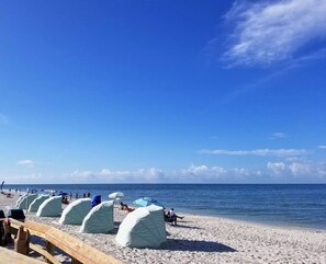 A beach with tents and a wooden fence.