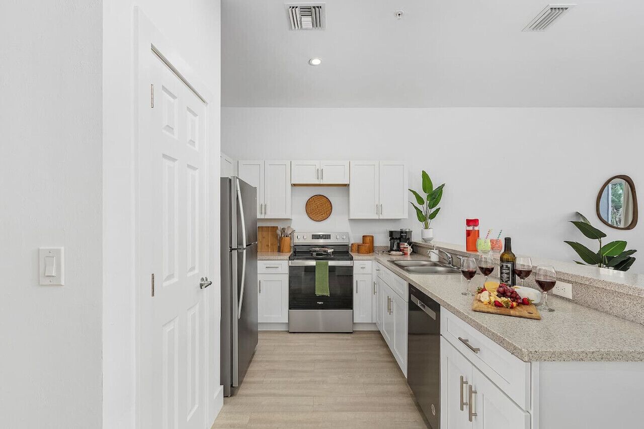 Una cocina moderna con armarios blancos, electrodomésticos de acero inoxidable y encimera de granito.