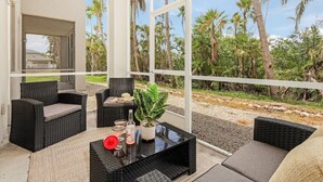 An outdoor patio with wicker furniture, a glass table, and a potted plant. - Paradise at Hidden Palms Cove (Fort Myers)