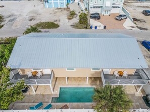 A two-story building with a flat roof, a swimming pool, and a covered patio area with seating. - Beach, pool time & fun times @ Blue Fish Lagoon (Fort Myers Beach)