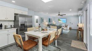 A modern kitchen with a dining area, a ceiling fan, and a large window with a view. - Beach, pool time & fun times @ Blue Fish Lagoon (Fort Myers Beach)