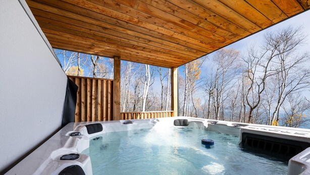 A hot tub with a wooden ceiling and a view of trees. - 61B Chalet: Hot Tub, River Views & Wood Accents (Petite-Rivière-Saint-François)