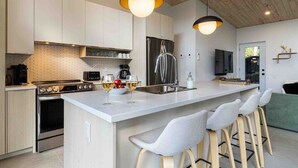Une cuisine moderne dotée d’un îlot central, d’appareils électroménagers en acier inoxydable et de tabourets de bar.