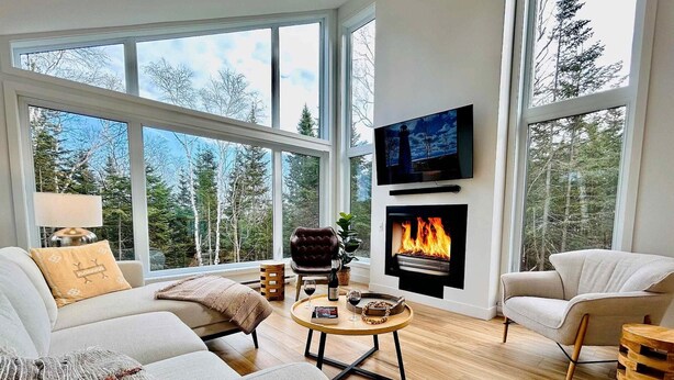 Una sala de estar moderna con chimenea, ventanas amplias y una zona de estar acogedora.