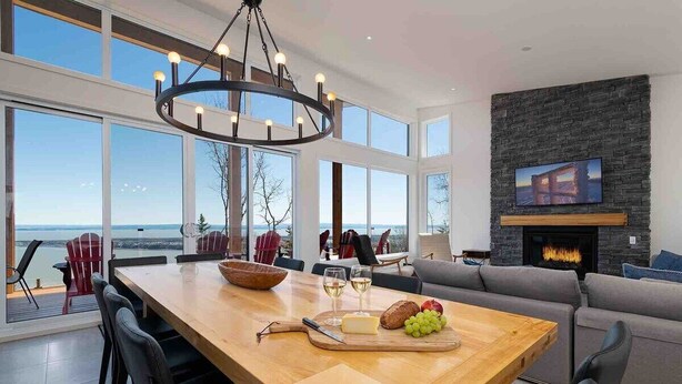 Un vaste espace dédié à la salle à manger, avec une grande table en bois, des chaises modernes et une vue sur l’extérieur.