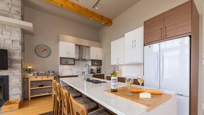 A modern kitchen with a central island, white cabinetry, and a built-in oven. - Le Méridien 33: Spa, River Views, Near Le Massif (Petite-Rivière-Saint-François)