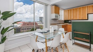 Une cuisine moderne avec un coin repas, de grandes fenêtres offrant une vue sur la ville et un mur d’accent de couleur verte.