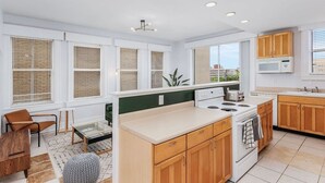 Une cuisine moderne avec des meubles blancs, un îlot central et une vue sur la ville.