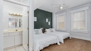 Une chambre avec deux lits, un dressing et un mur d’accent de couleur verte.