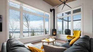 Een moderne woonkamer met een groot raam, een open haard en een bank met kussens.