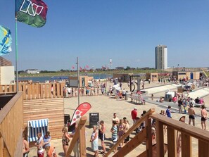 Un espace aménagé au bord de la plage, avec des structures en bois, une piscine et une vue sur la mer.