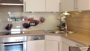 A modern kitchen with stainless steel appliances, a wooden countertop, and a white backsplash. - Watt's Happiness Close to the Beach (Büsum)