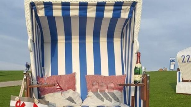 A beach chair with striped fabric, two cushions, and a small table with a bottle. - Watt's Happiness Close to the Beach (Büsum)