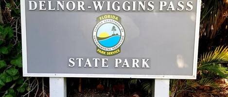 A sign for Delnor-Wiggins Pass State Park with the Florida Department of Environmental Protection logo.
