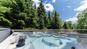 Ein Whirlpool, umgeben von einer Holzterrasse und dichtem Wald.
