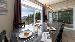 Un coin repas avec une table dressée pour deux personnes, un journal et un croissant sur une assiette.
