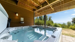 Un bain à remous doté d’un plafond en bois et offrant une vue sur la mer.