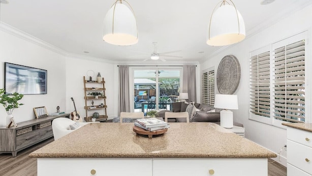 Een moderne keuken met een centraal eiland, witte kasten en hangende lampen.