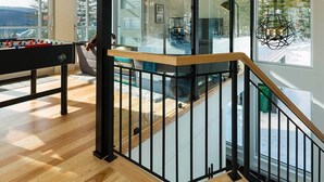 A modern interior with a wooden ceiling, glass walls, a staircase, and a foosball table. - Le Rupin 77: River, Mountain Views & Hot Tub (Charlevoix)