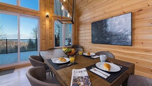 Un comedor con mesa de madera, sillas y un ventanal con vistas a una terraza.