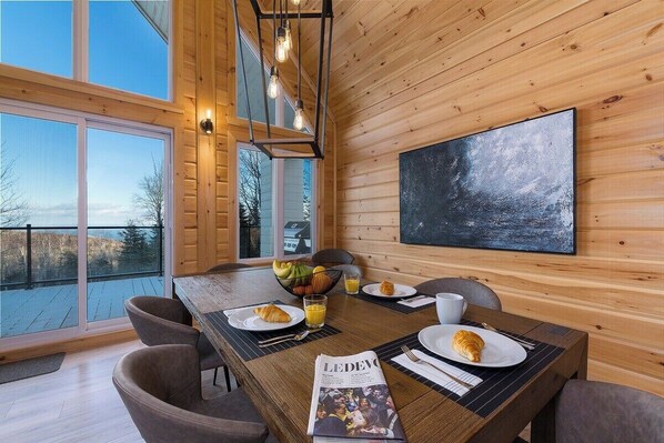 Enjoy meals in this stylish dining area with a long table set for two, featuring a blackboard on the wall.