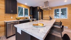 Una cocina moderna con paredes de madera, encimera de mármol y una isla central con asientos.