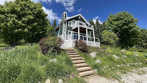A two-story house with a porch and a staircase leading up to it. - 14B Condo: Mountain & River Views, Terrace & BBQ (Petite-Rivière-Saint-François)