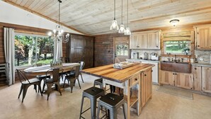 Une cuisine moderne avec des meubles en bois, un grand îlot central, des tabourets de bar et des luminaires suspendus.