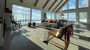 A spacious living room with large windows, a wooden ceiling, and a cozy seating area.