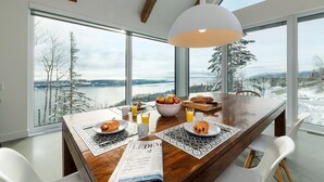 A dining area with a large table, breakfast items, and a view of a snowy landscape through large windows.